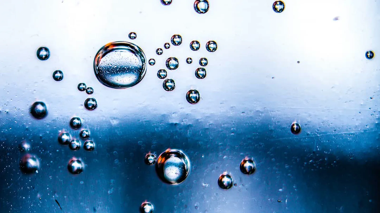 Bolhas de ar sobre superfície azul e branca, refletindo pontos de luz