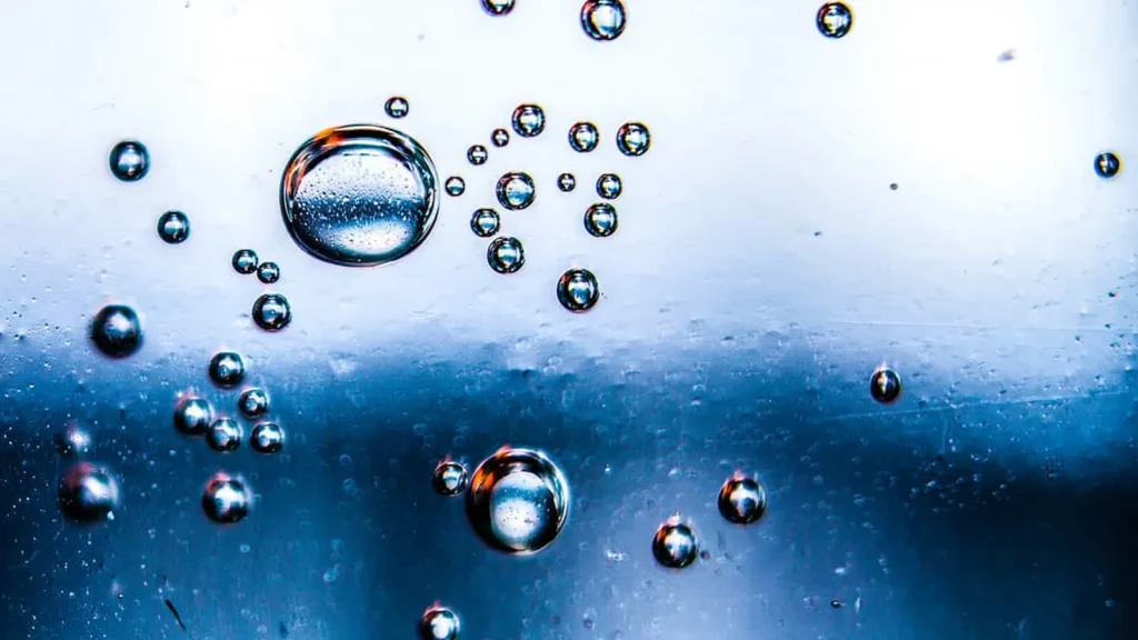 Bolhas de ar sobre superfície azul e branca, refletindo pontos de luz