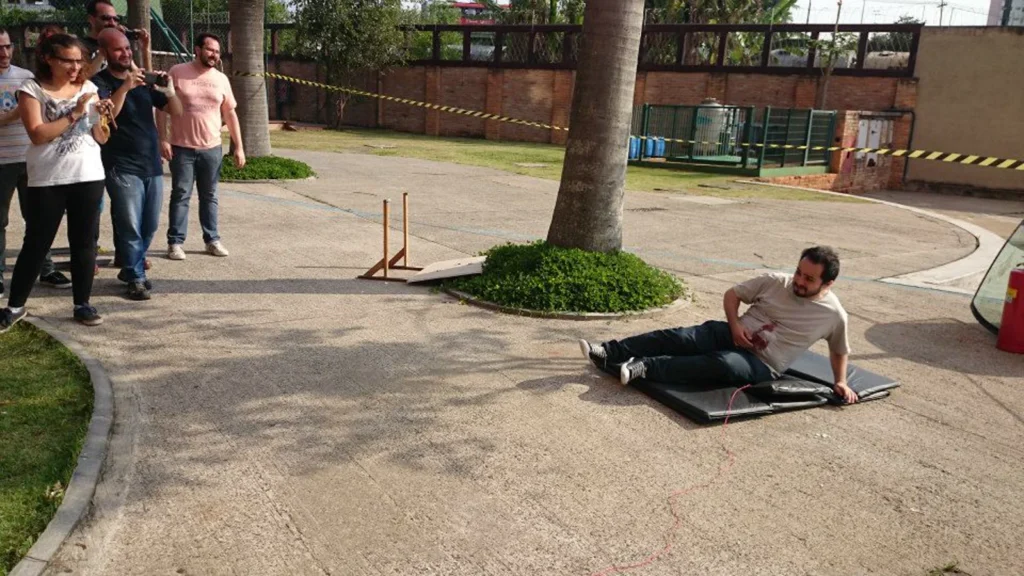 Participante deitado sobre o colchão logo após o disparo da carga de tiro cênico, com o grupo em volta