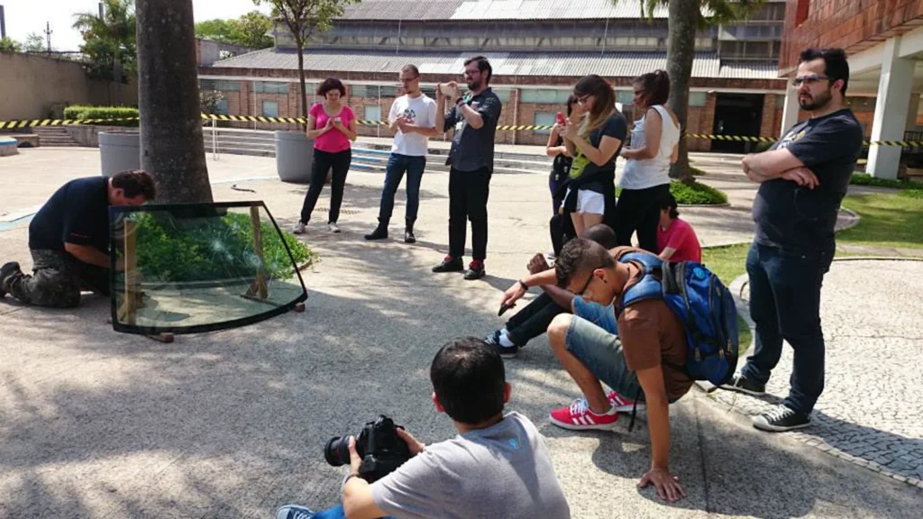 Vidro de carro estilhaçado pela carga de tiro, com o grupo fotografando o resultado