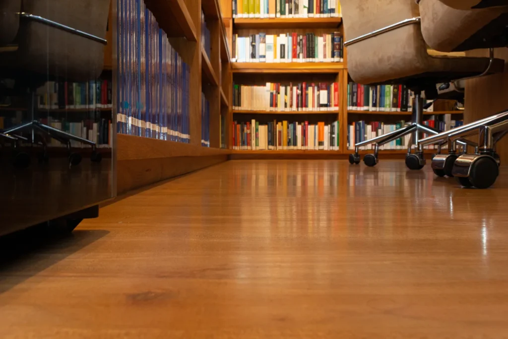 Corredor da biblioteca do escritório, estantes de livros à direita e piso de madeira em fuga